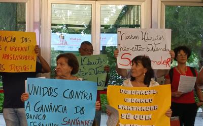 Imagem mostra manifestantes aposentados do Santander portando cartazes